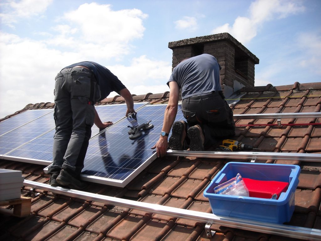 Dos técnicos instalan paneles de energía solar en una casa.