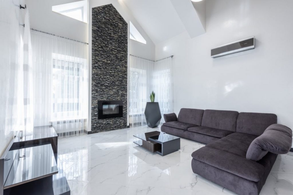 Salón de vivienda con sofá y aire acondicionado de aerotermia